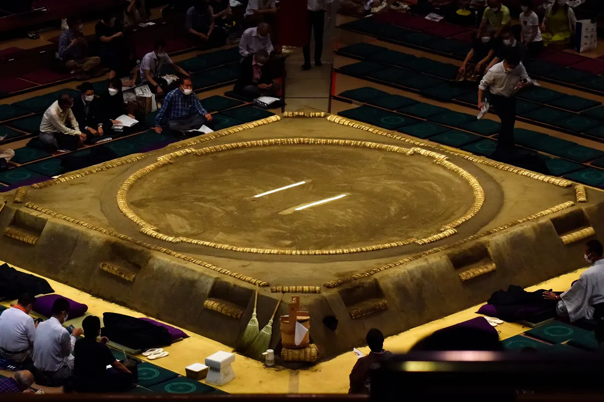 Ein Sumo-Ring aus der Vogelperspektive, mit einem Kreis aus Reisstrohballen auf einer erhöhten Lehmplattform in einer Arena